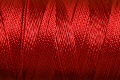 Photo of Spool of red sewing thread as background, closeup