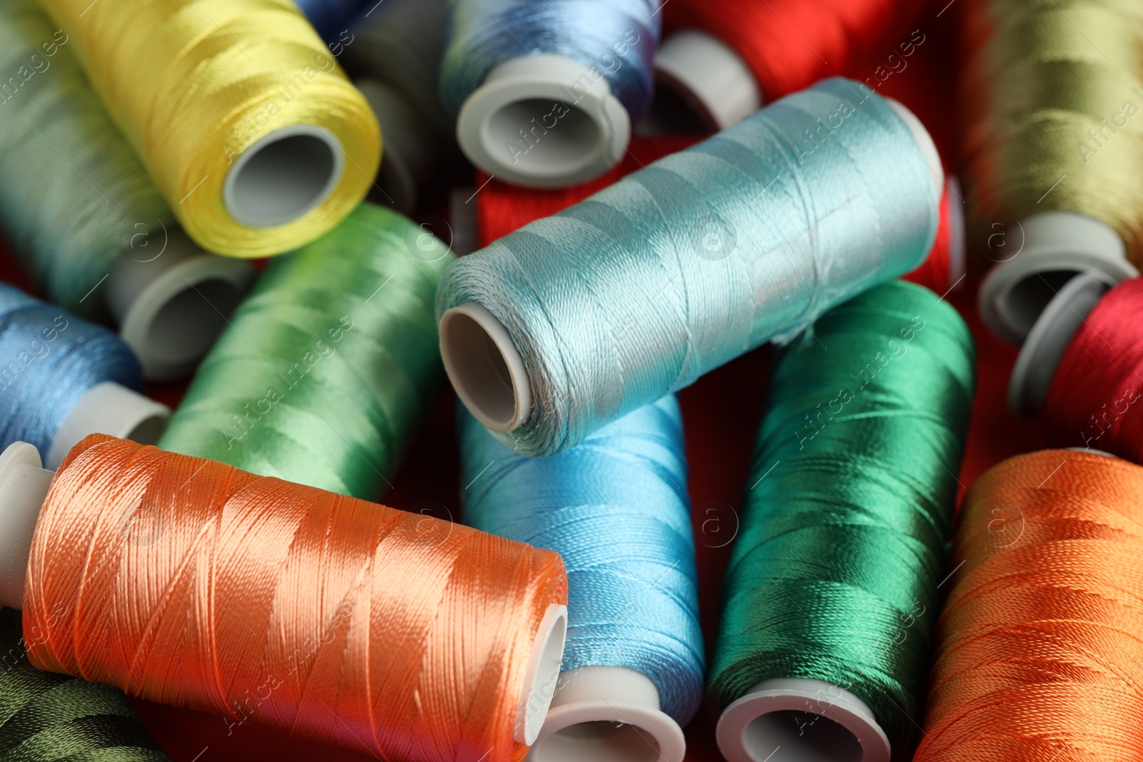 Photo of Different spools of sewing threads as background, closeup