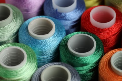 Photo of Different spools of sewing threads as background, closeup