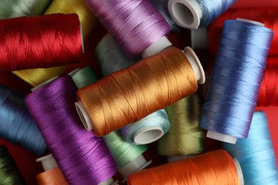 Photo of Different spools of sewing threads as background, closeup