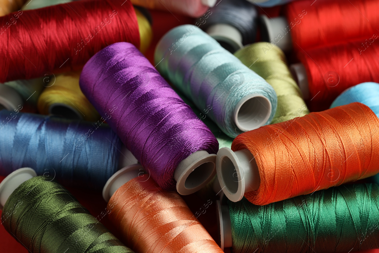 Photo of Different spools of sewing threads as background, closeup