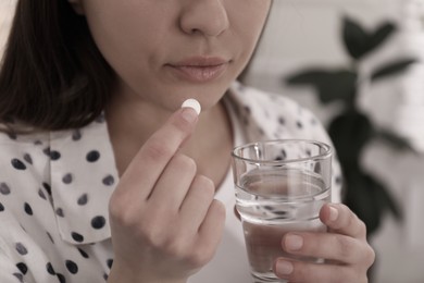 Image of Young woman taking pill indoors, closeup. Toned for dramatic atmosphere