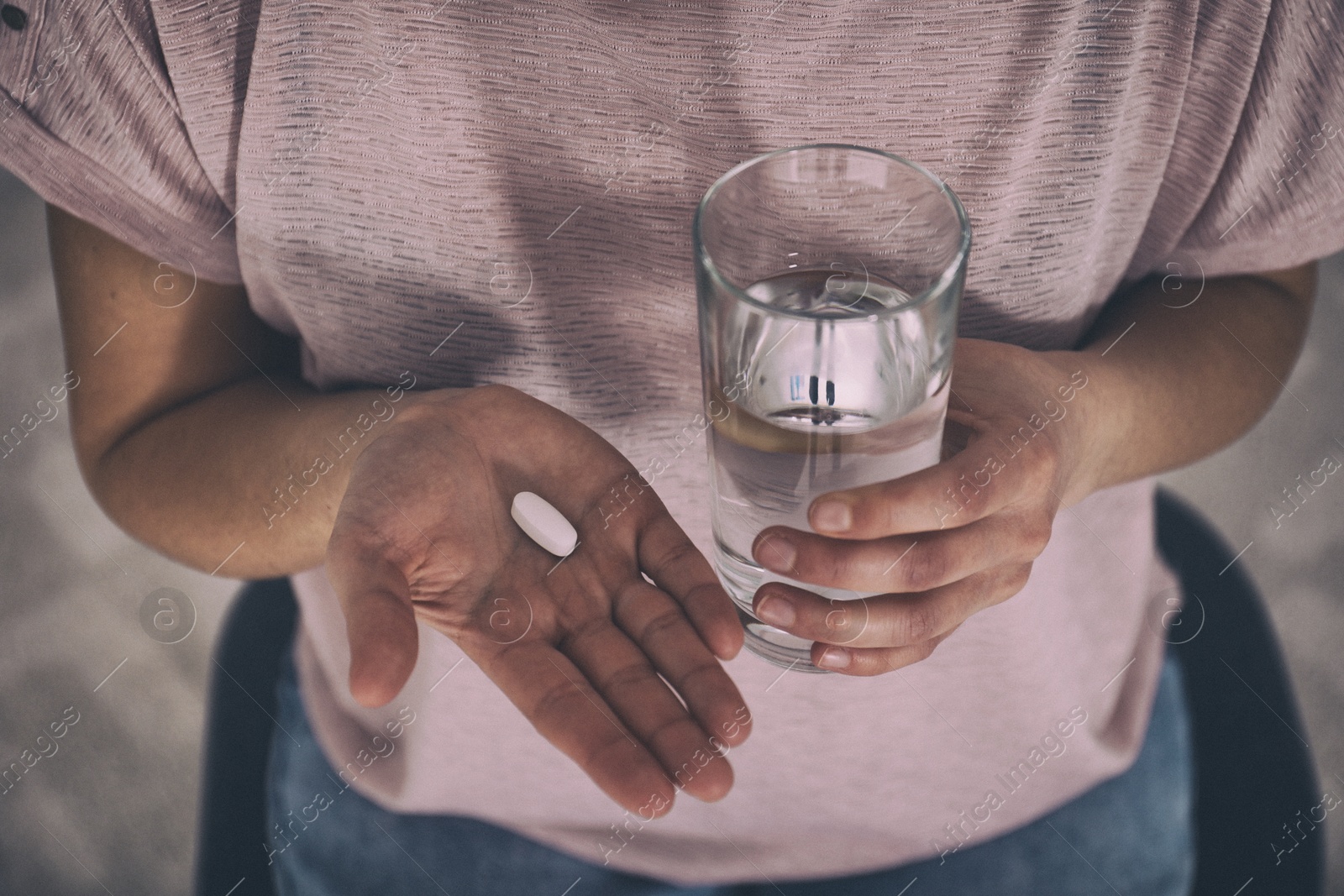 Image of Young woman with pill and glass of water indoors, closeup. Toned for dramatic atmosphere