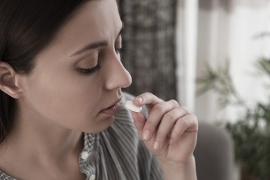 Image of Young woman taking pill indoors, closeup. Toned for dramatic atmosphere