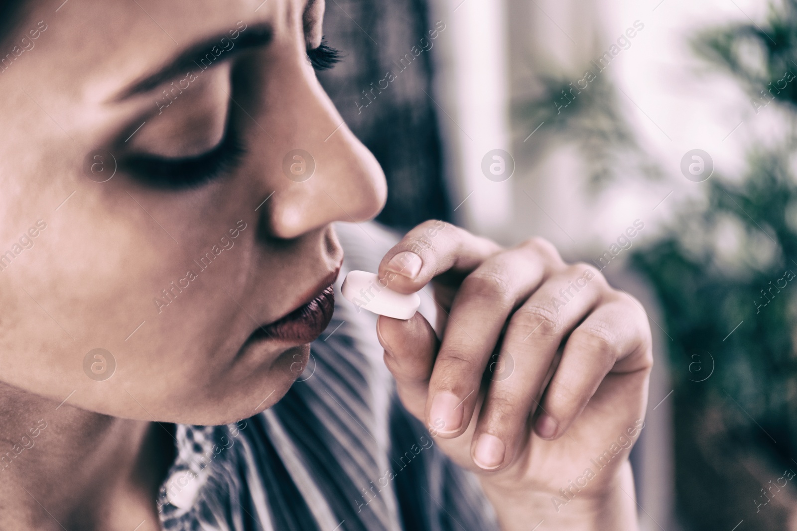 Image of Young woman taking pill indoors, closeup. Toned for dramatic atmosphere