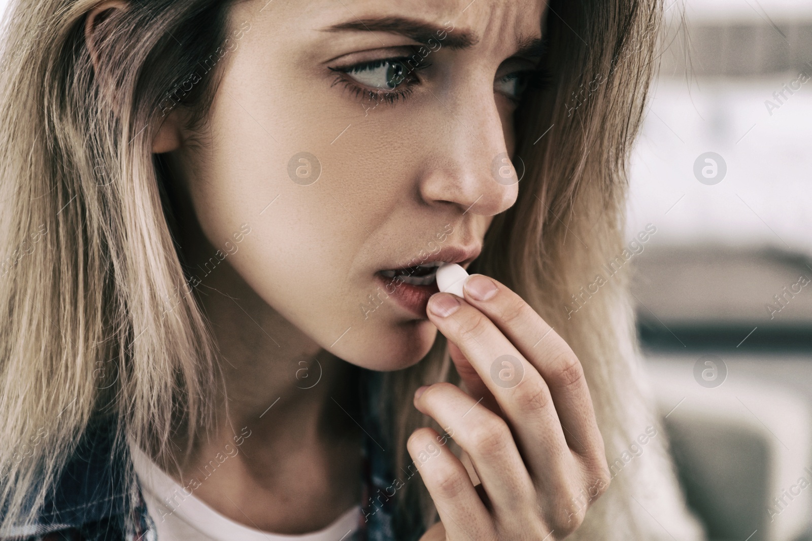 Image of Sad young woman taking pill indoors, closeup. Toned for dramatic atmosphere