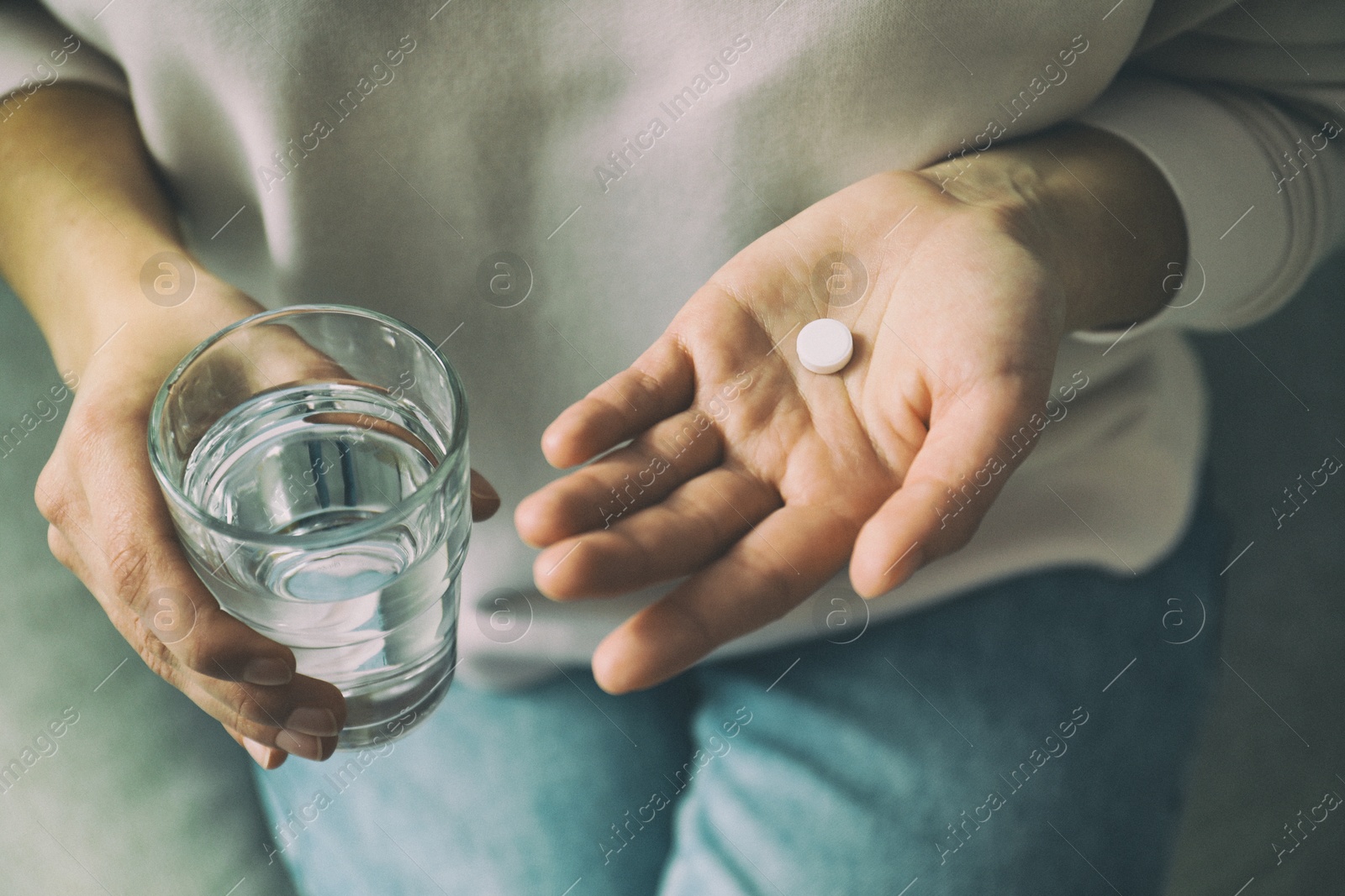 Image of Young woman with pill and glass of water indoors, closeup. Toned for dramatic atmosphere