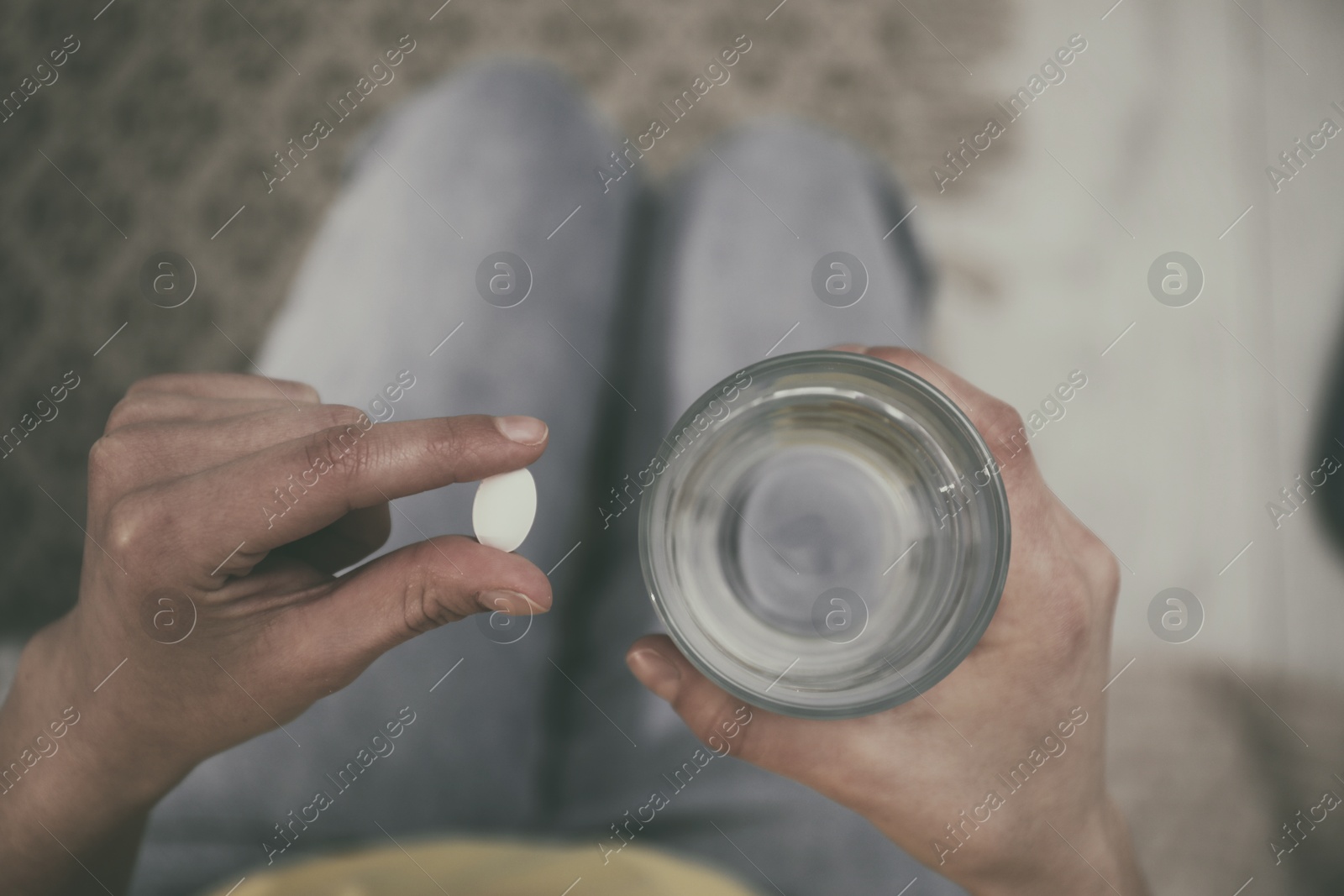 Image of Young woman with pill and glass of water indoors, top view. Toned for dramatic atmosphere