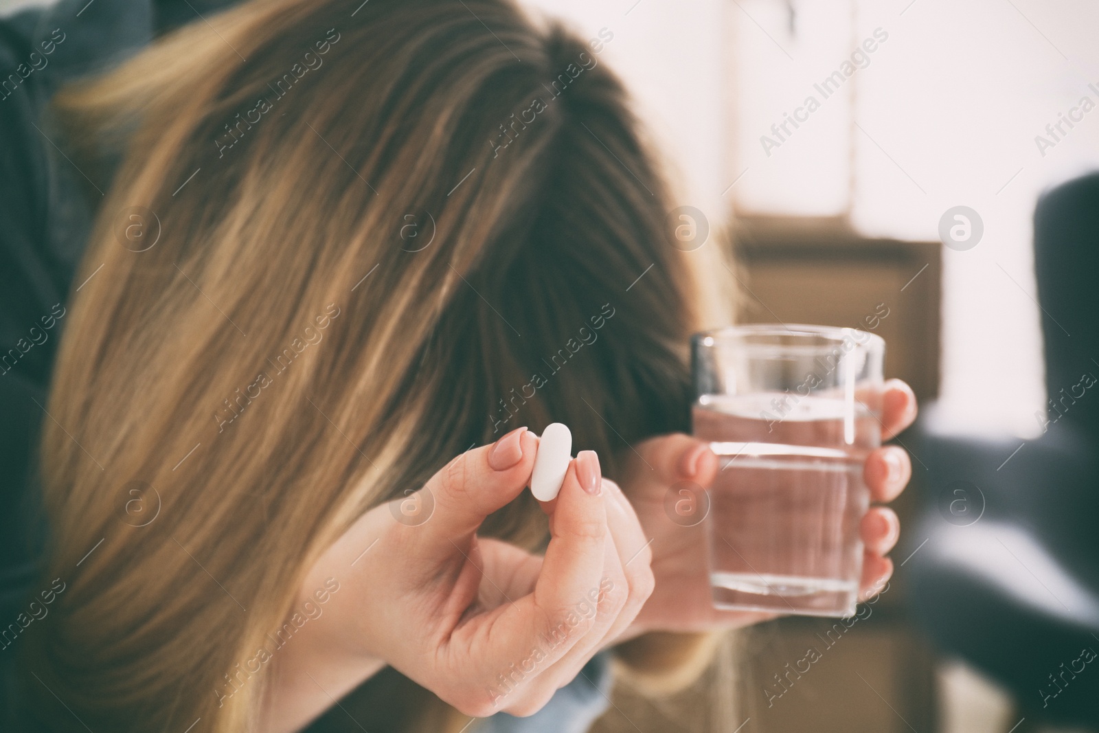 Image of Sad young woman with pill and glass of water indoors, closeup. Toned for dramatic atmosphere