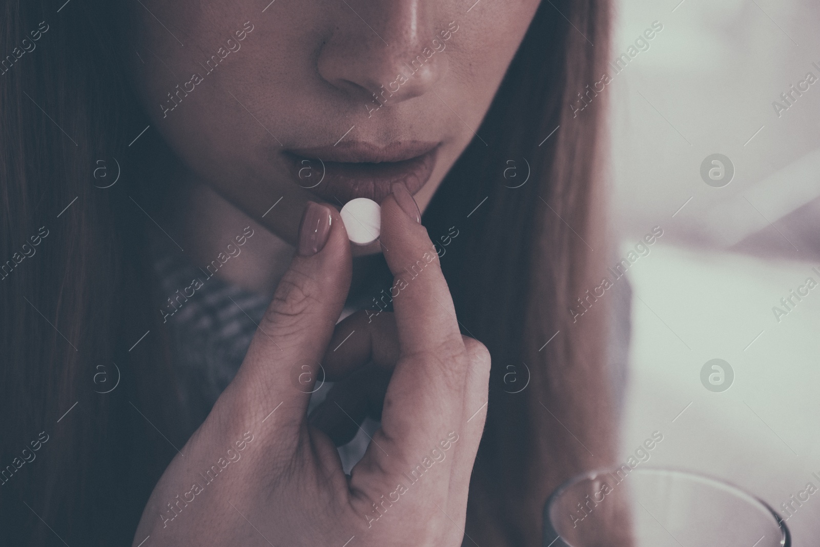 Image of Young woman taking pill indoors, closeup. Toned for dramatic atmosphere