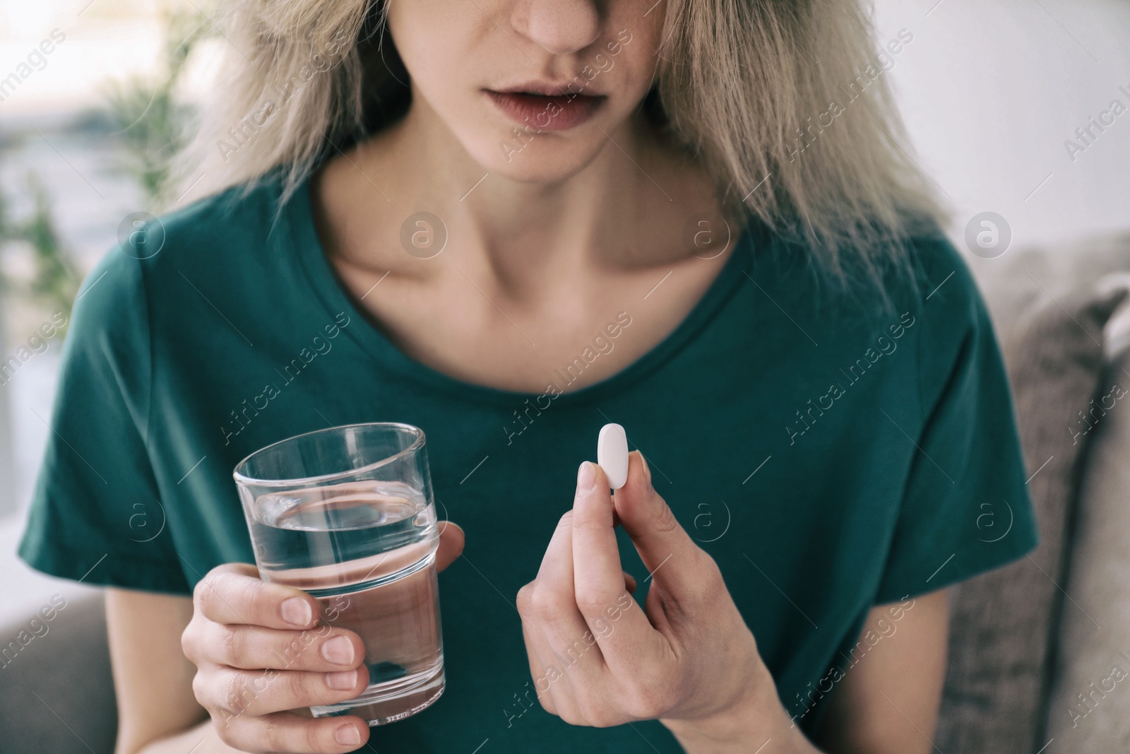 Image of Young woman with pill and glass of water indoors, closeup. Toned for dramatic atmosphere