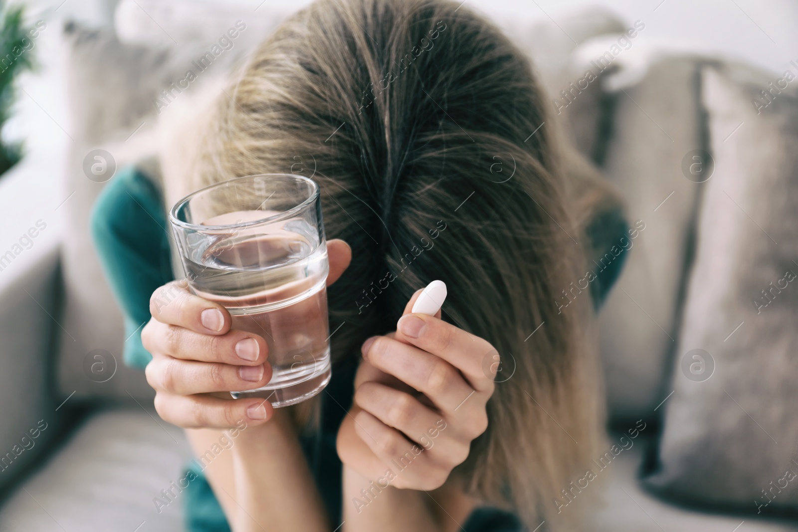 Image of Sad young woman with pill and glass of water indoors, closeup. Toned for dramatic atmosphere