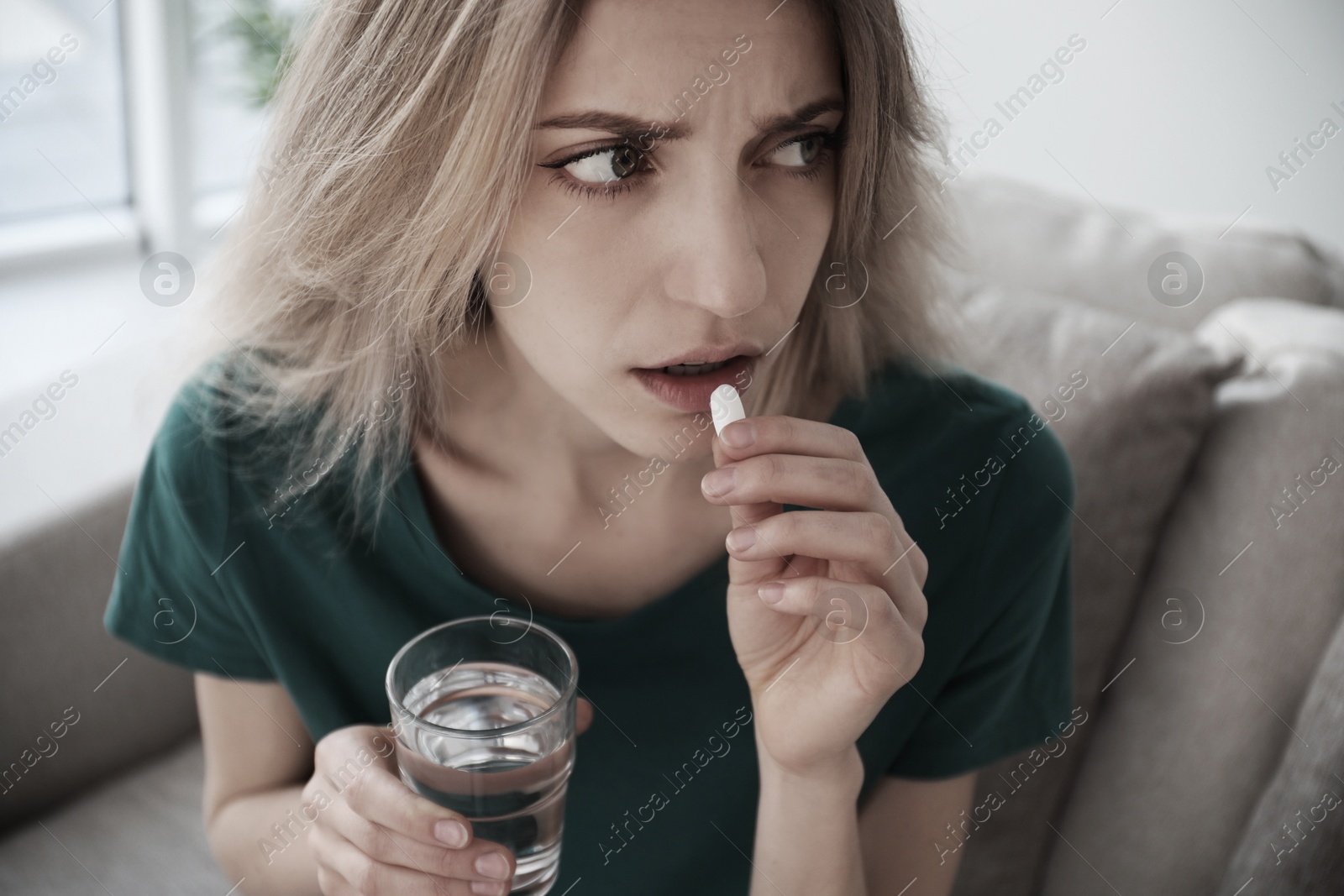 Image of Sad young woman taking pill indoors, closeup. Toned for dramatic atmosphere