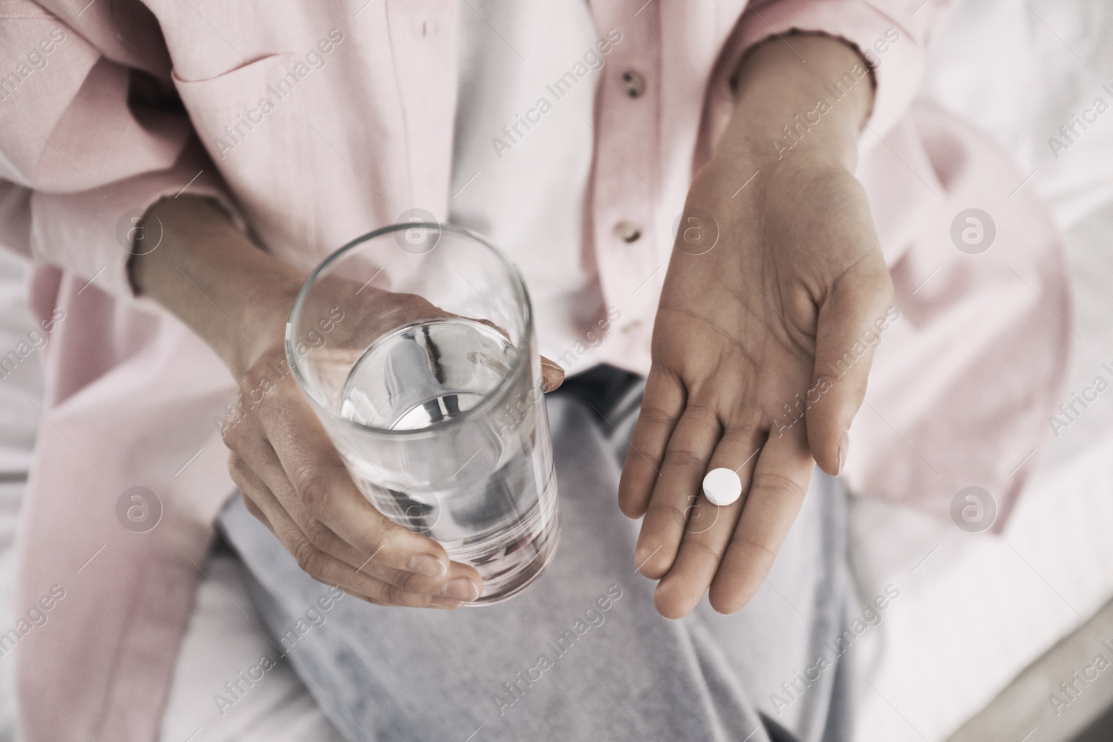 Image of Young woman with pill and glass of water indoors, closeup. Toned for dramatic atmosphere