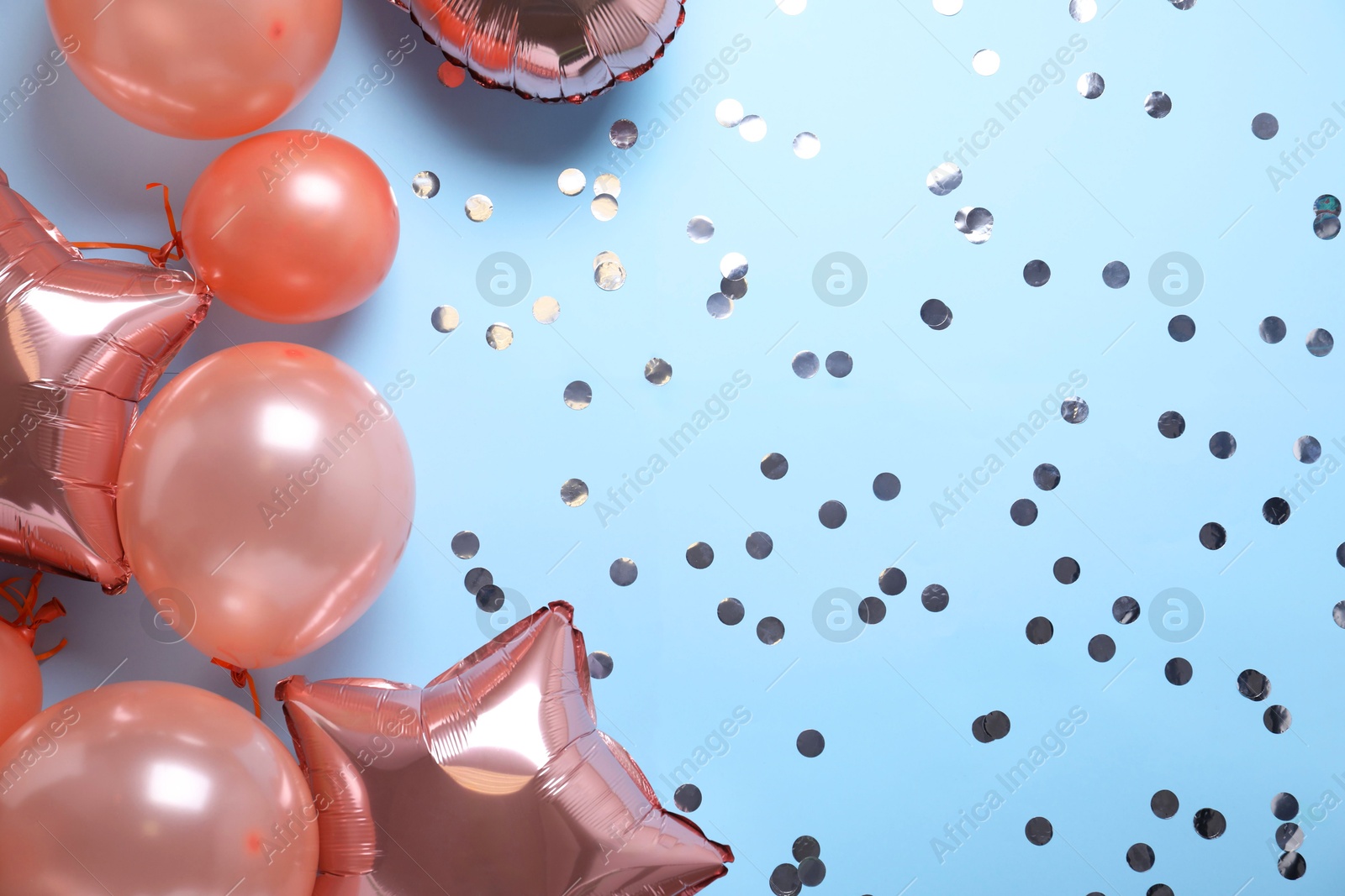 Photo of Colorful balloons and confetti on light blue background, flat lay. Space for text