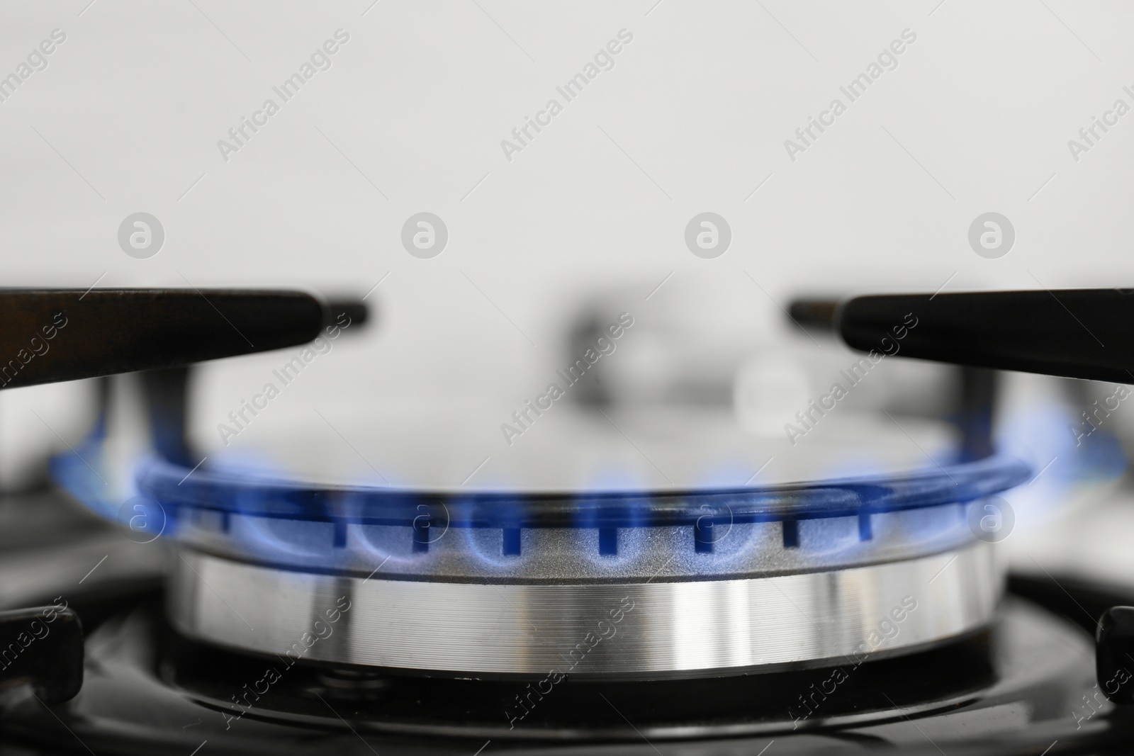 Photo of Gas burner of modern stove with burning blue flame, closeup