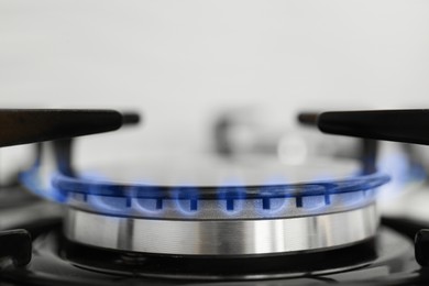 Photo of Gas burner of modern stove with burning blue flame, closeup