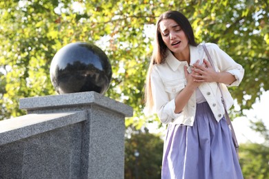 Young woman having heart attack in park