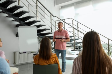 Photo of Male lecturer in casual clothes talking to audience indoors