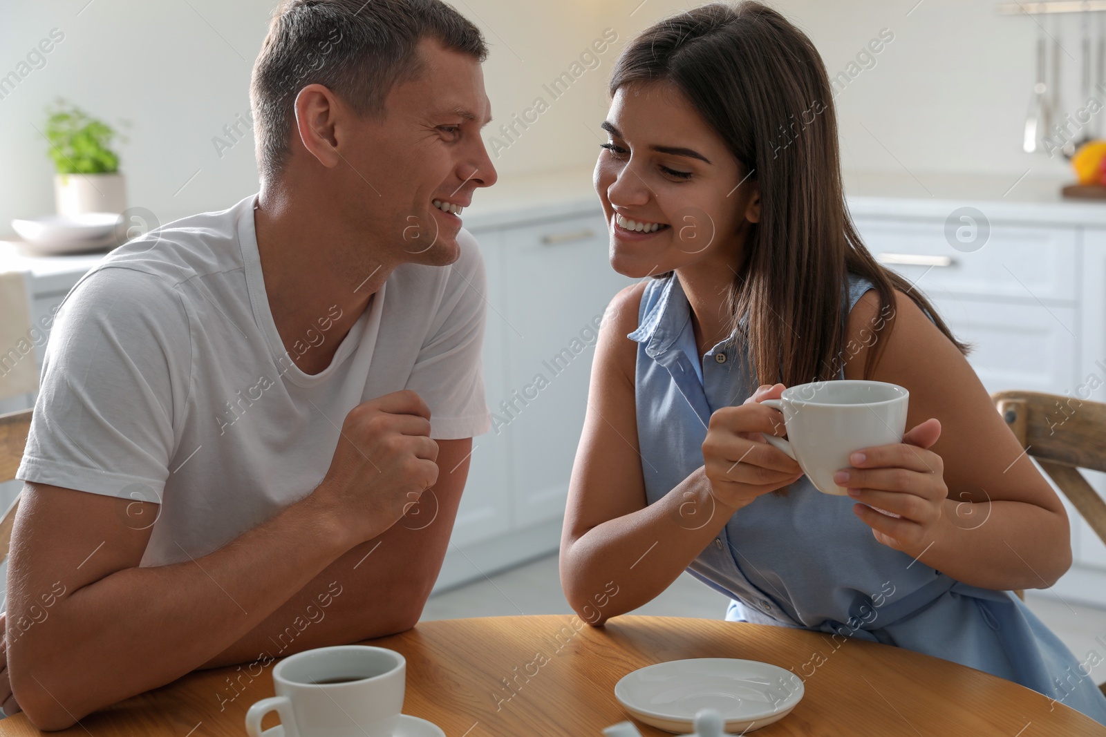 Photo of Man and woman talking while drinking tea at table in kitchen