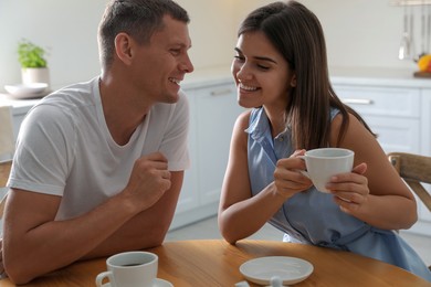 Man and woman talking while drinking tea at table in kitchen