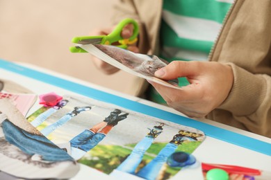 Photo of Creating vision board. Little boy cutting out picture at table indoors, closeup