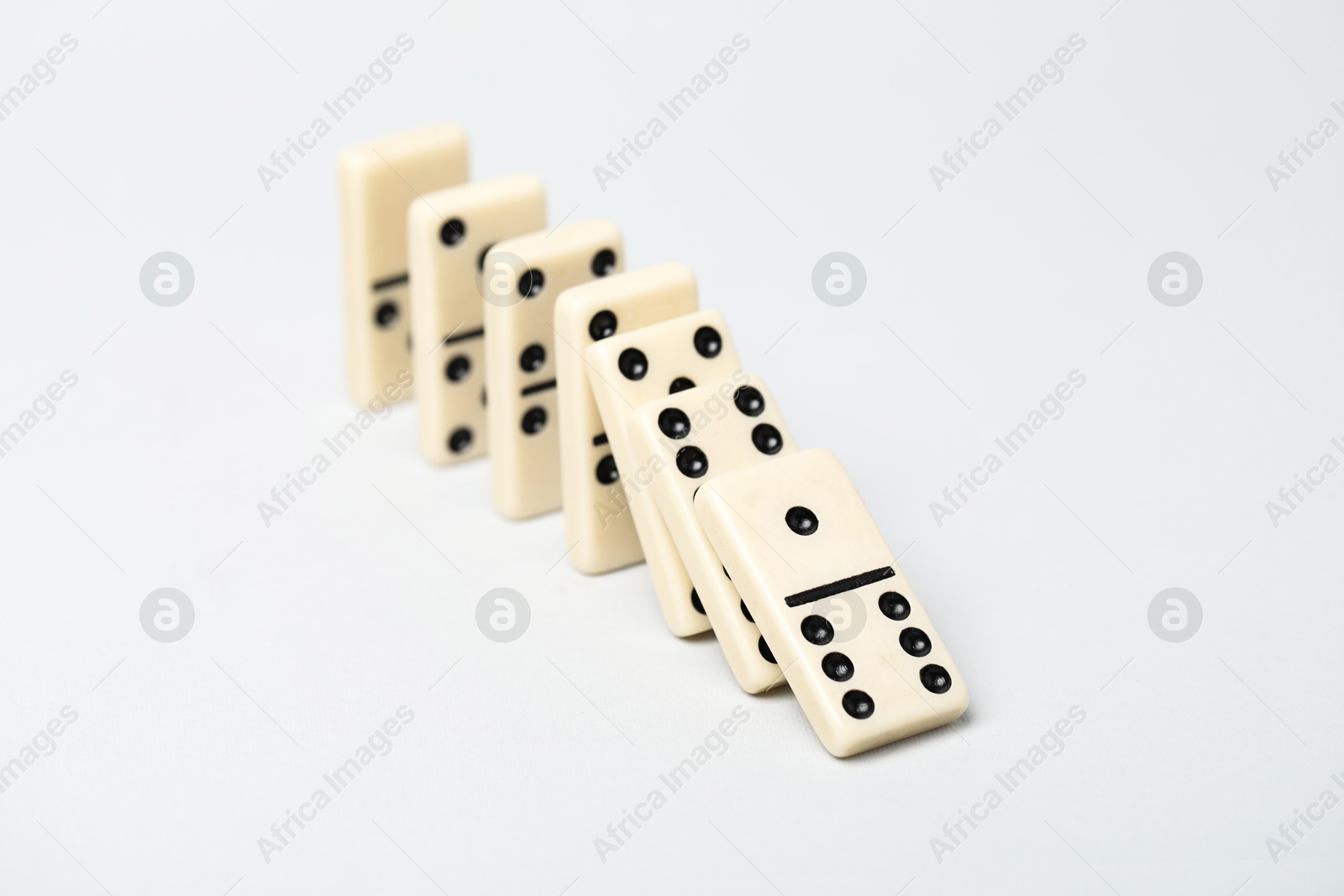 Photo of Domino effect. Tiles falling on light background