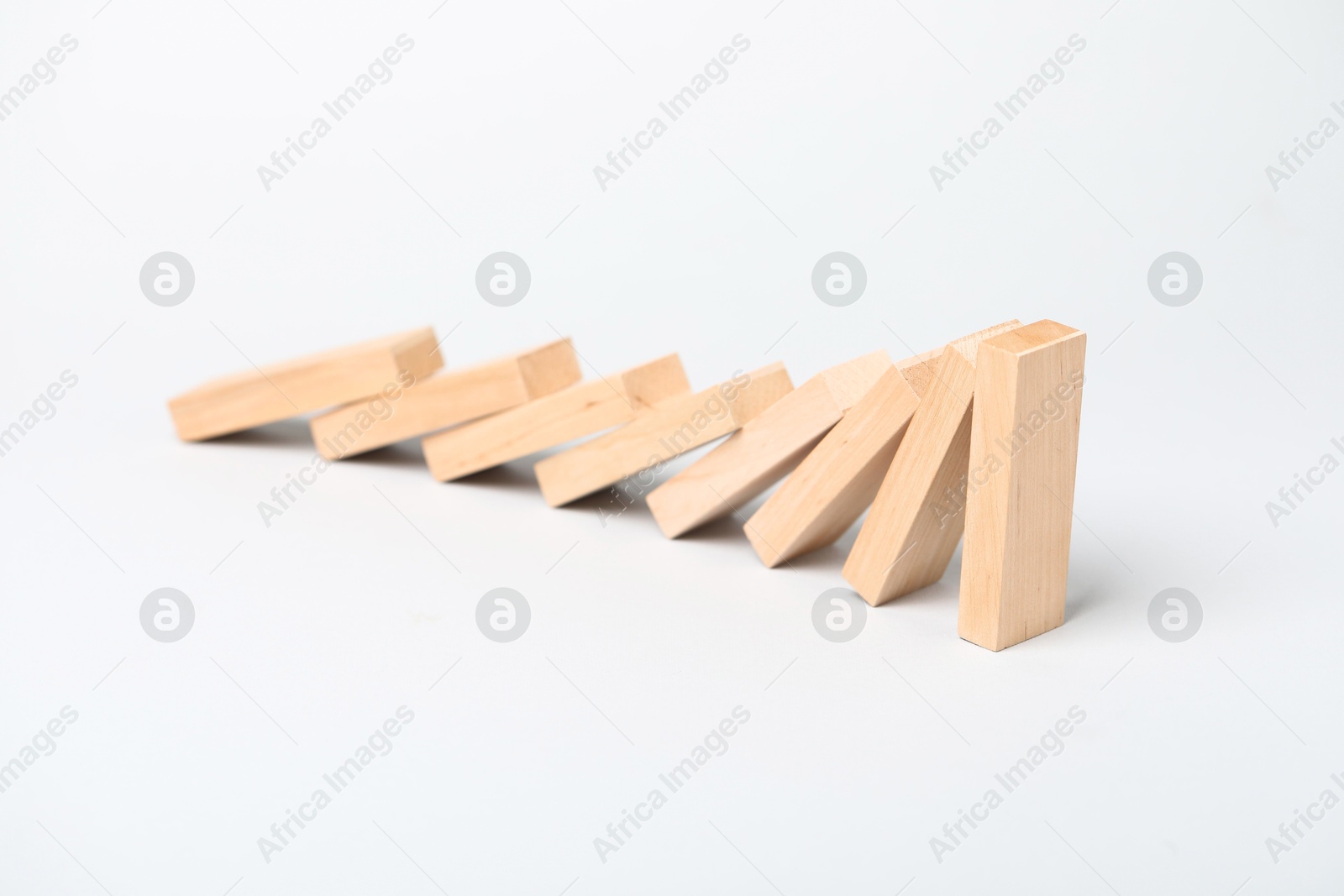 Photo of Domino effect. Wooden blocks falling on light background