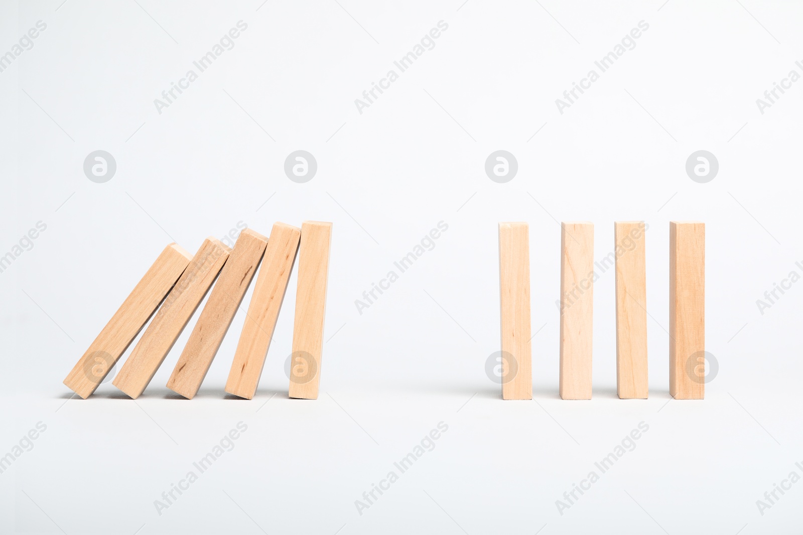 Photo of Domino effect. Wooden blocks falling on light background