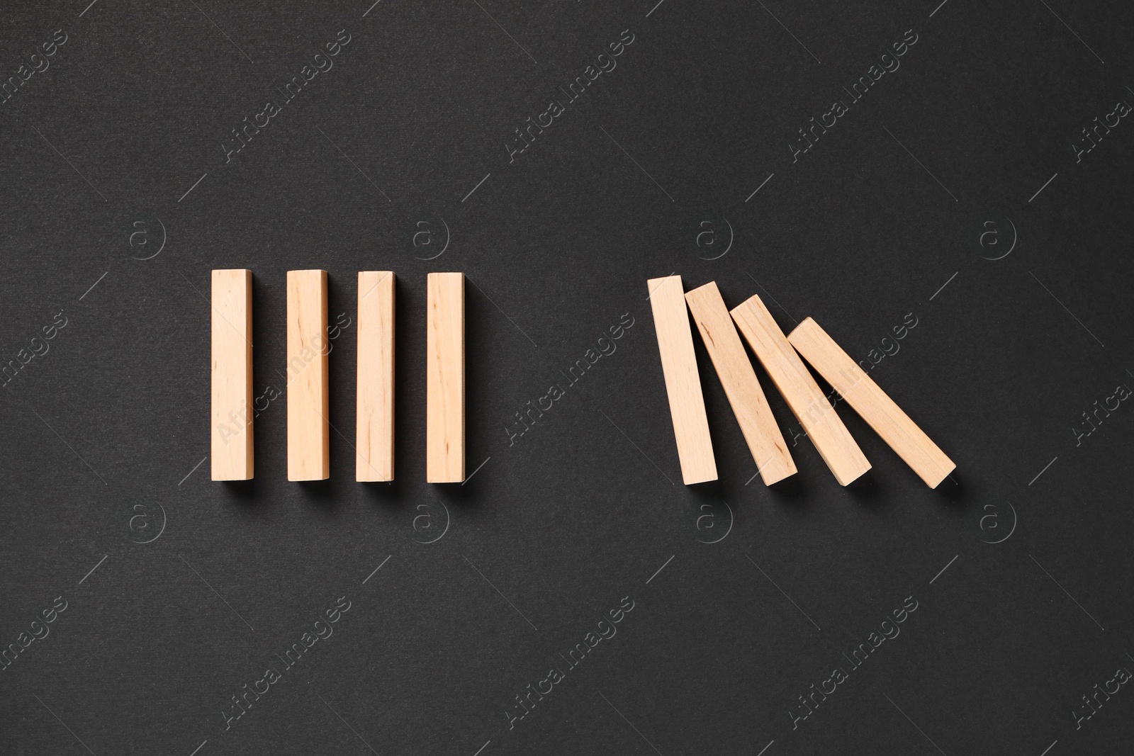 Photo of Domino effect. Wooden blocks on black background, flat lay