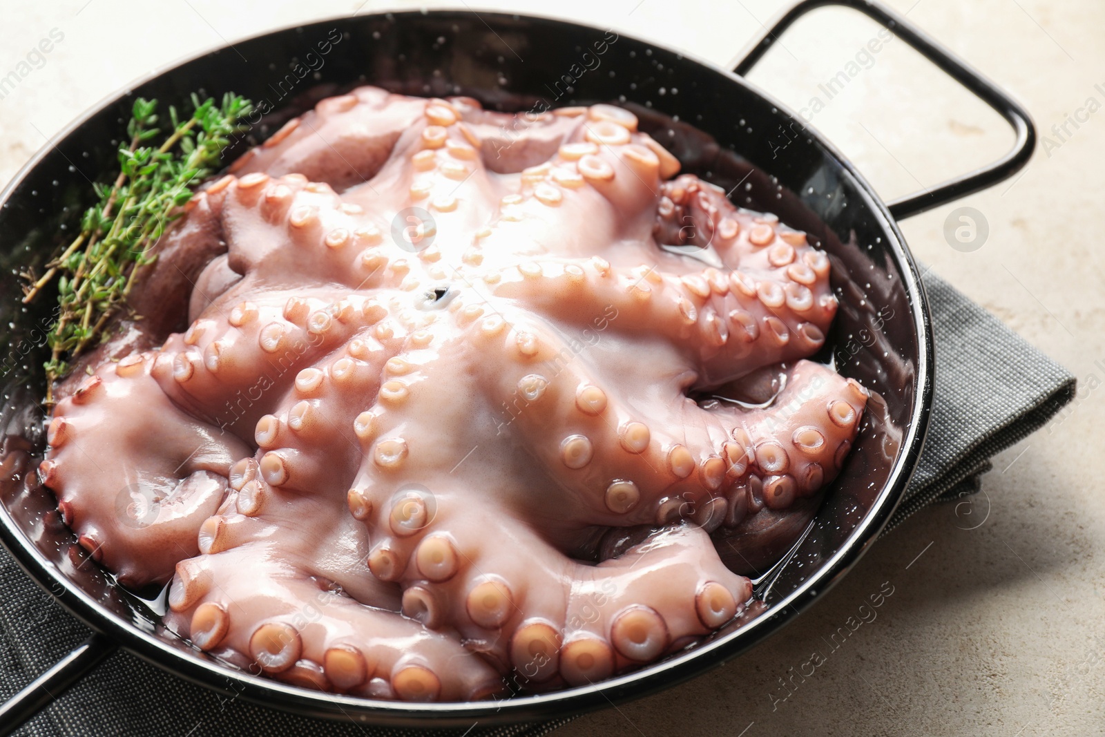 Photo of Fresh raw octopus and thyme in frying pan on grey table, closeup