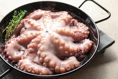 Photo of Fresh raw octopus and thyme in frying pan on grey table, closeup