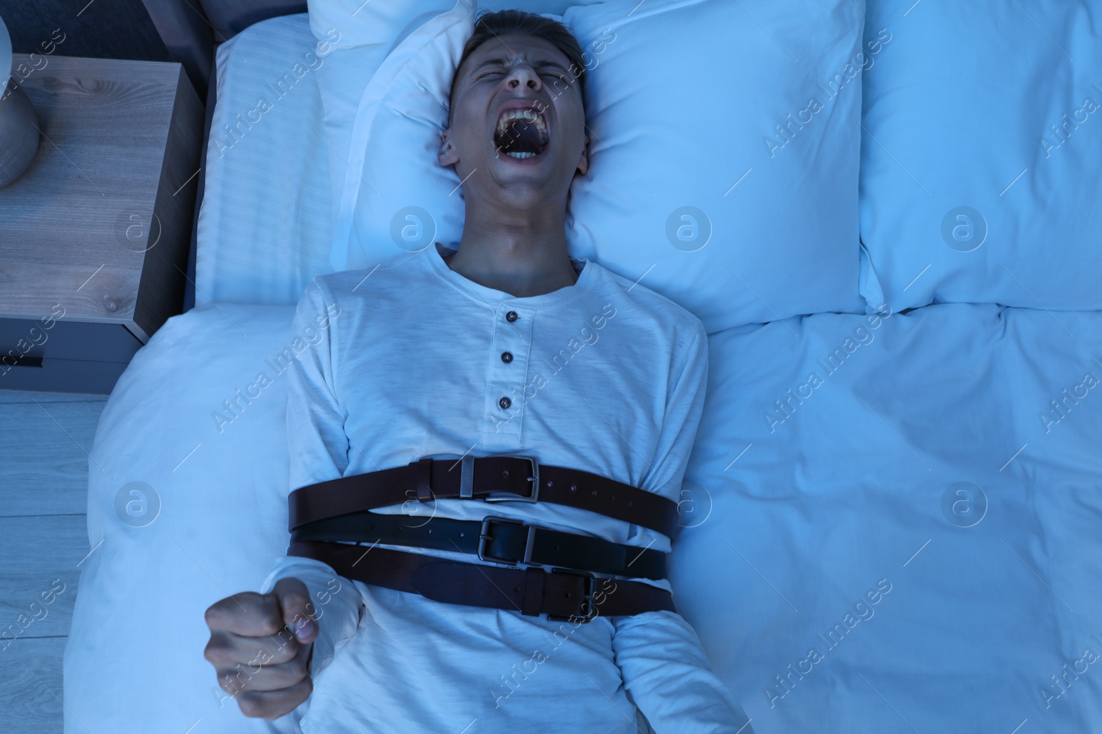 Photo of Man in sleepwalking condition screaming on bed, top view