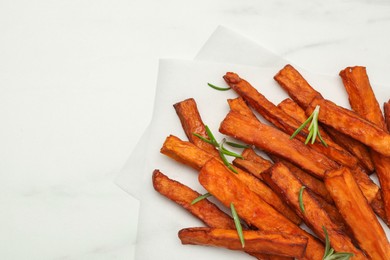 Photo of Delicious sweet potato fries with rosemary on white table, top view. Space for text