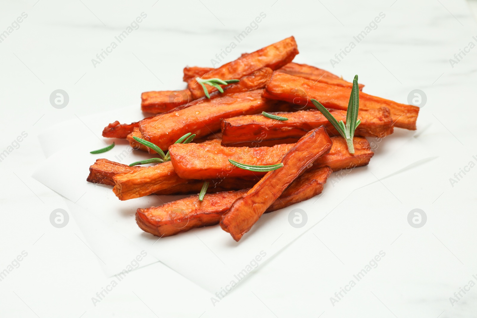 Photo of Delicious sweet potato fries with rosemary on white table, closeup