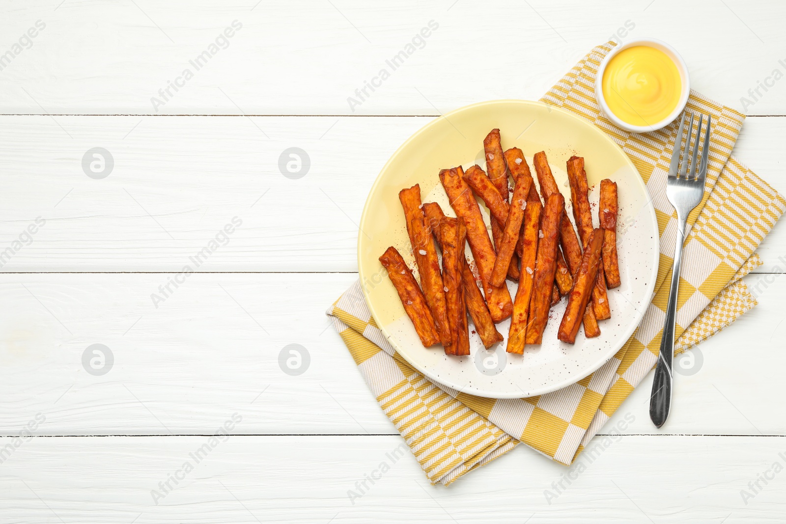 Photo of Delicious sweet potato fries and sauce on white wooden table, top view. Space for text