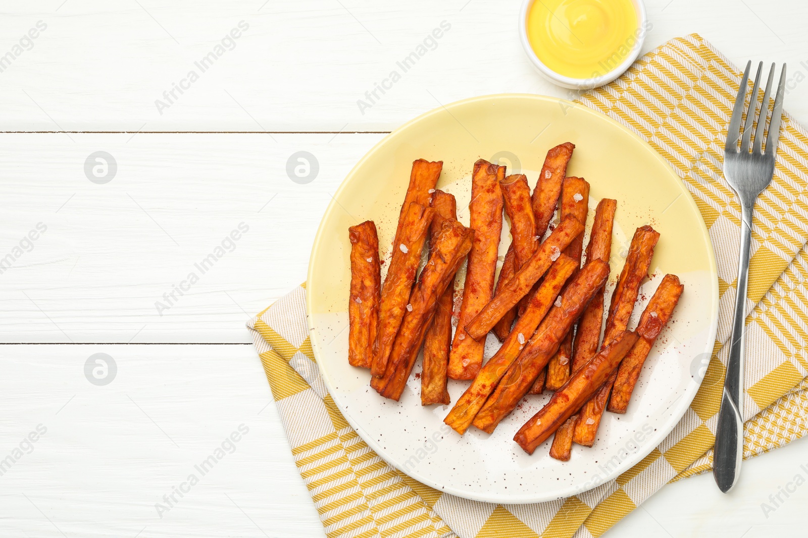 Photo of Delicious sweet potato fries and sauce on white wooden table, top view. Space for text