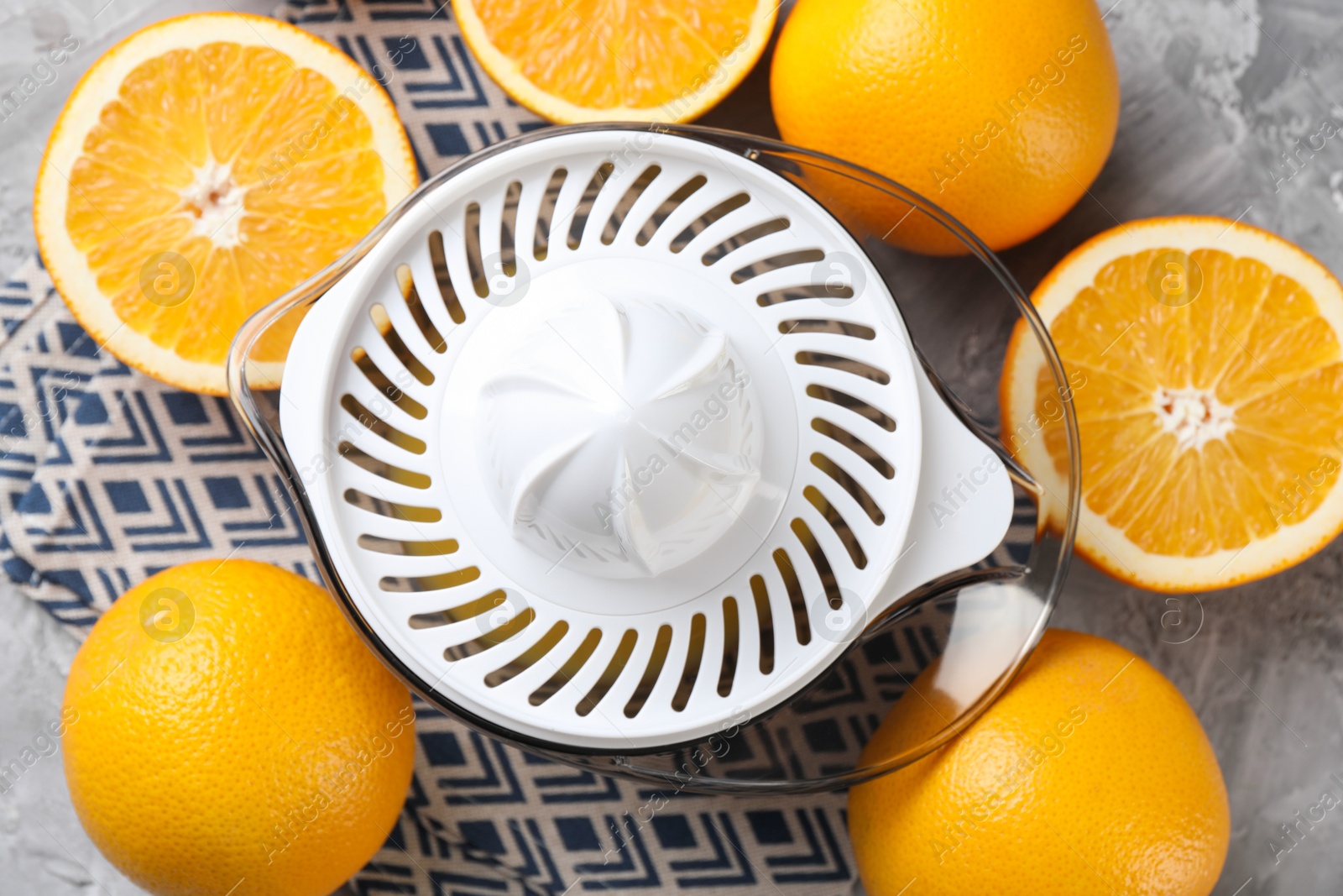 Photo of Plastic juicer and oranges on grey table, top view