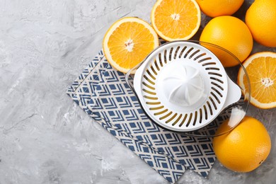 Photo of Plastic juicer and oranges on grey table, top view. Space for text