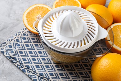 Photo of Plastic juicer and oranges on grey table, closeup