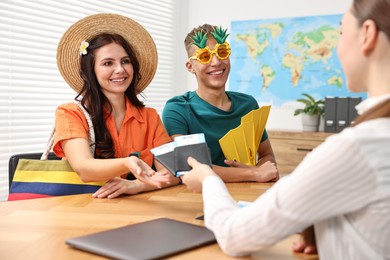 Photo of Happy couple planning vacation with travel agent at wooden table in office