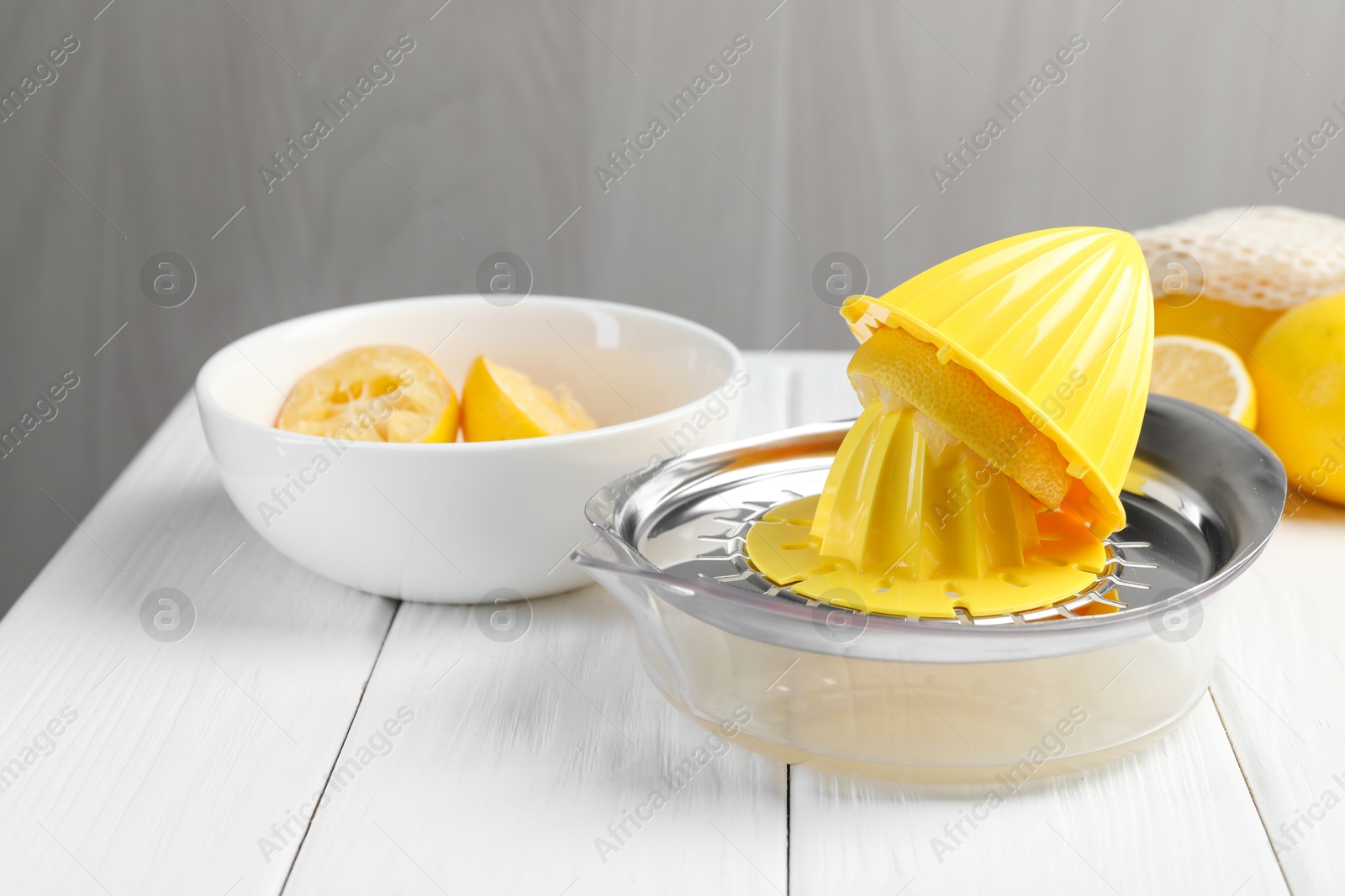 Photo of Plastic juicer and fresh lemons on white wooden table, closeup