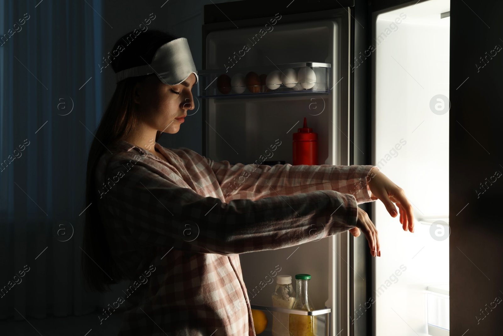 Photo of Young woman suffering from sleepwalking near fridge at home