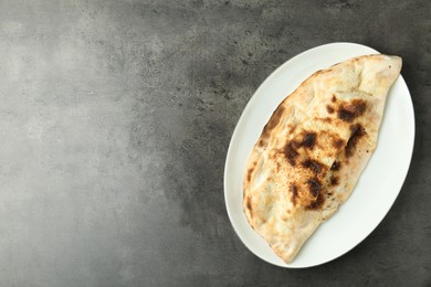 Photo of One delicious calzone on grey textured table, top view. Space for text