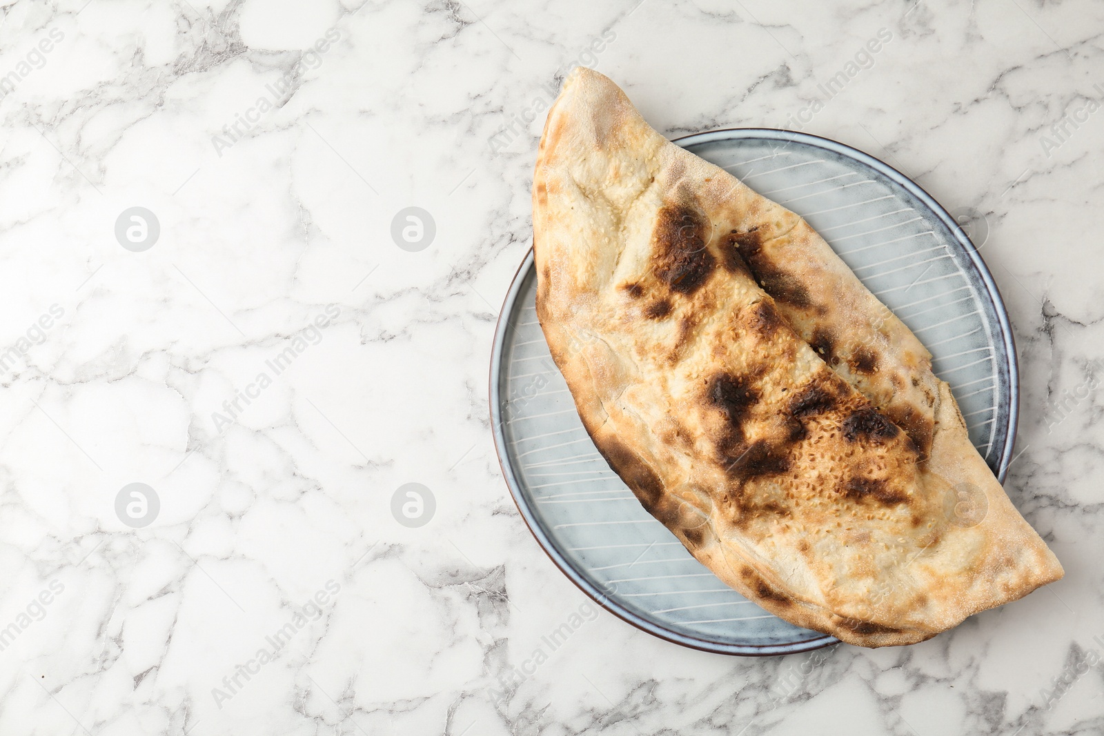 Photo of Delicious calzone on white marble table, top view. Space for text