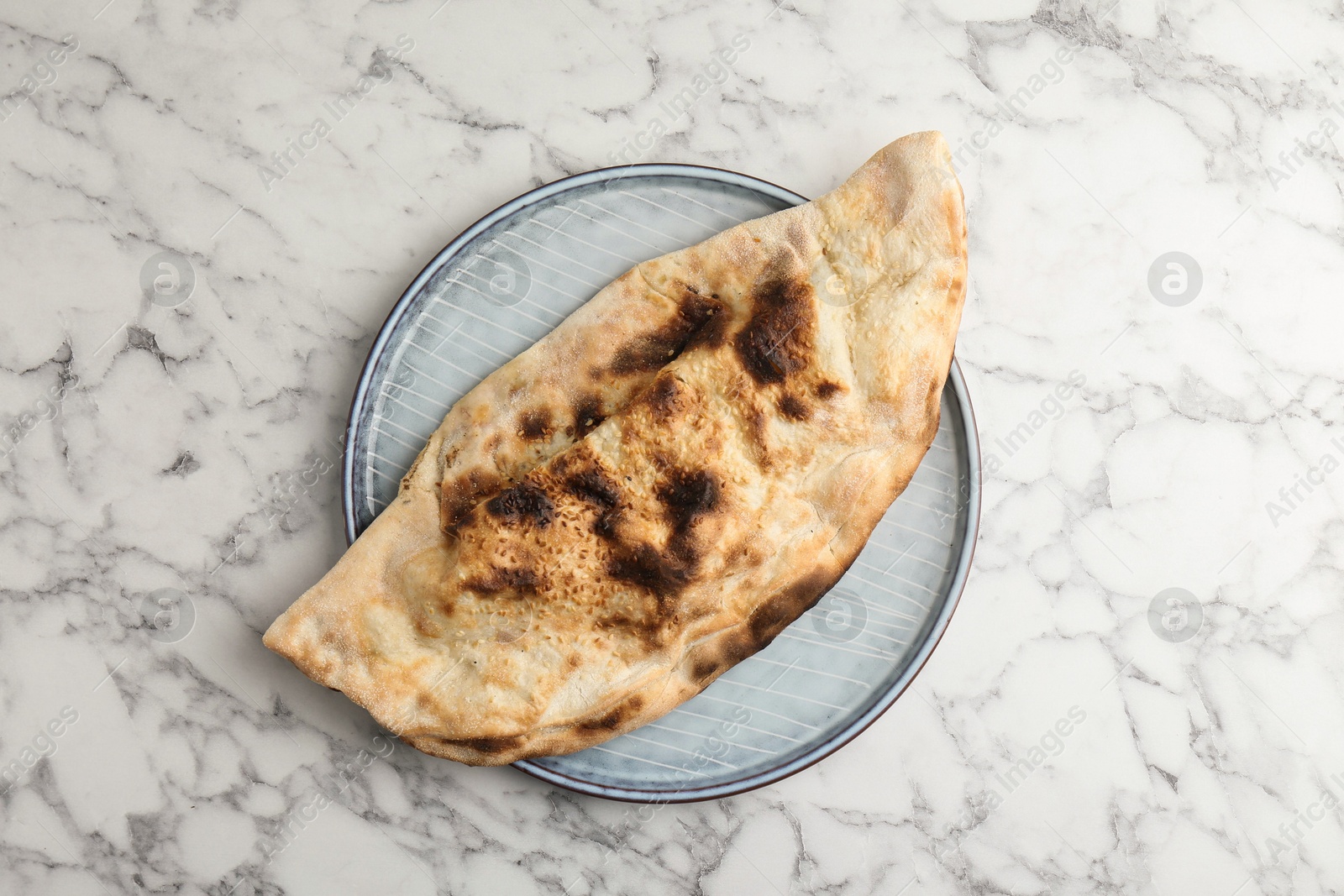 Photo of Delicious calzone on white marble table, top view