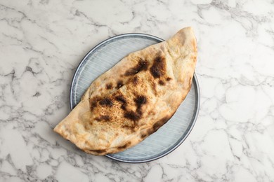 Photo of Delicious calzone on white marble table, top view