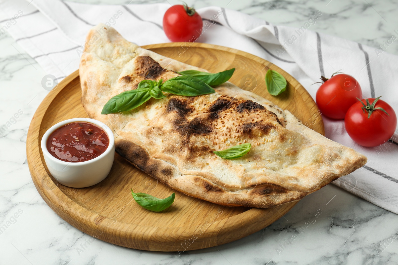 Photo of Delicious calzone served on white marble table