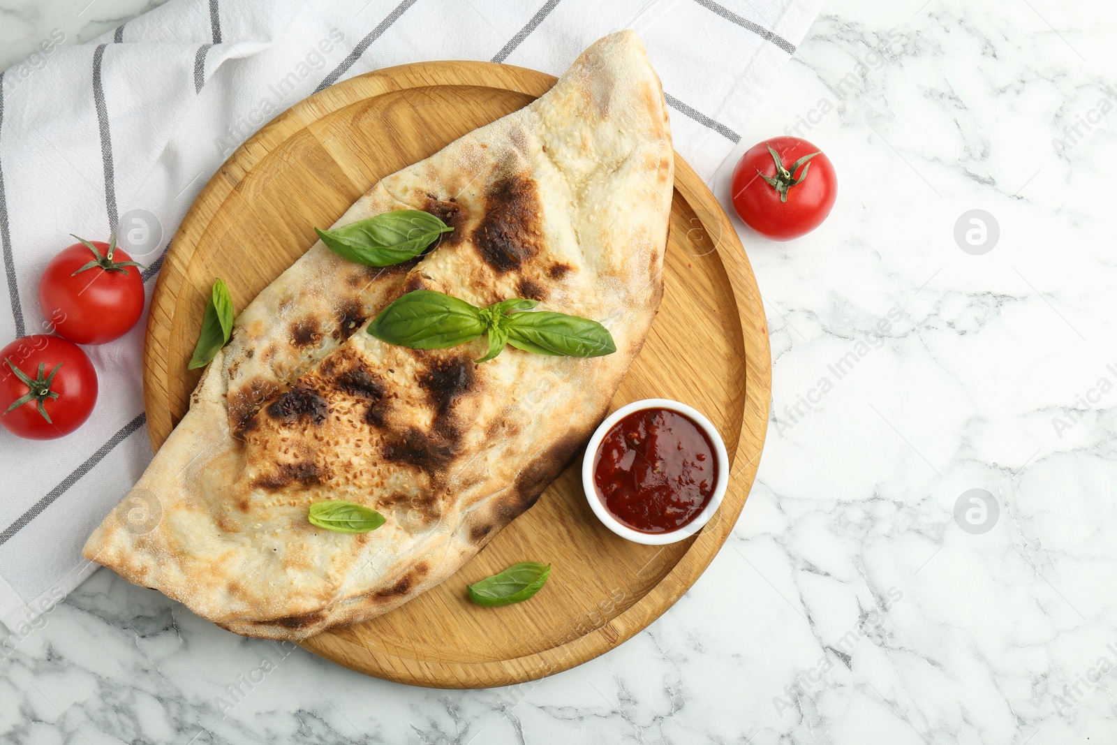 Photo of Delicious calzone served on white marble table, top view. Space for text