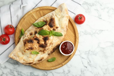 Photo of Delicious calzone served on white marble table, top view. Space for text